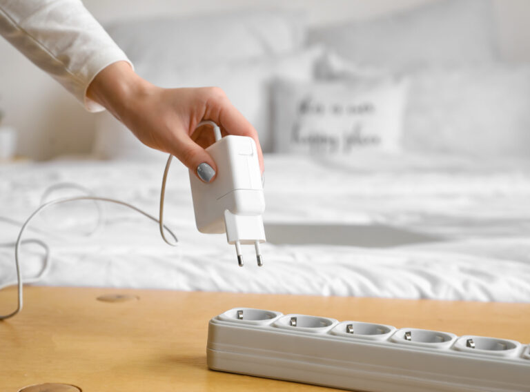 Woman putting plug into extension cord in bedroom